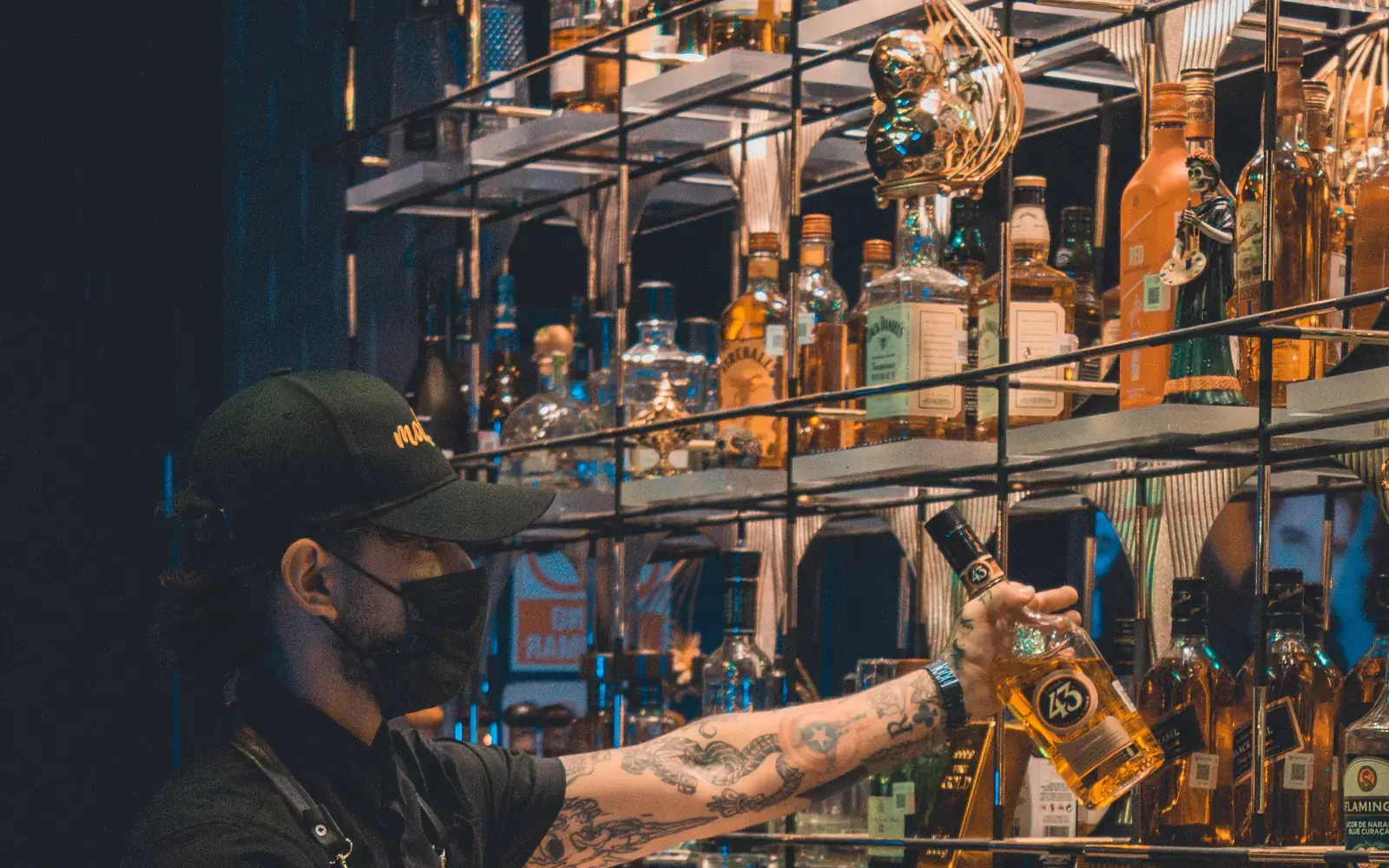 Bartender taking a liquor bottle from a back-bar shelf