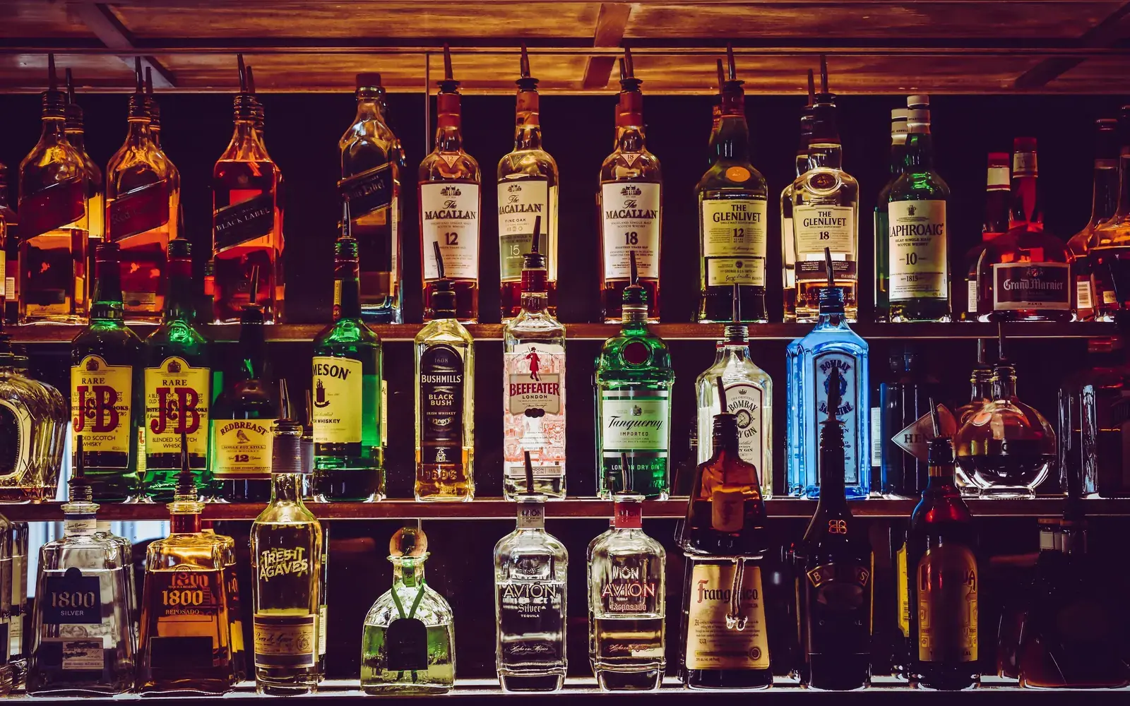 Rows of liquor bottles lined up on a back-bar shelf