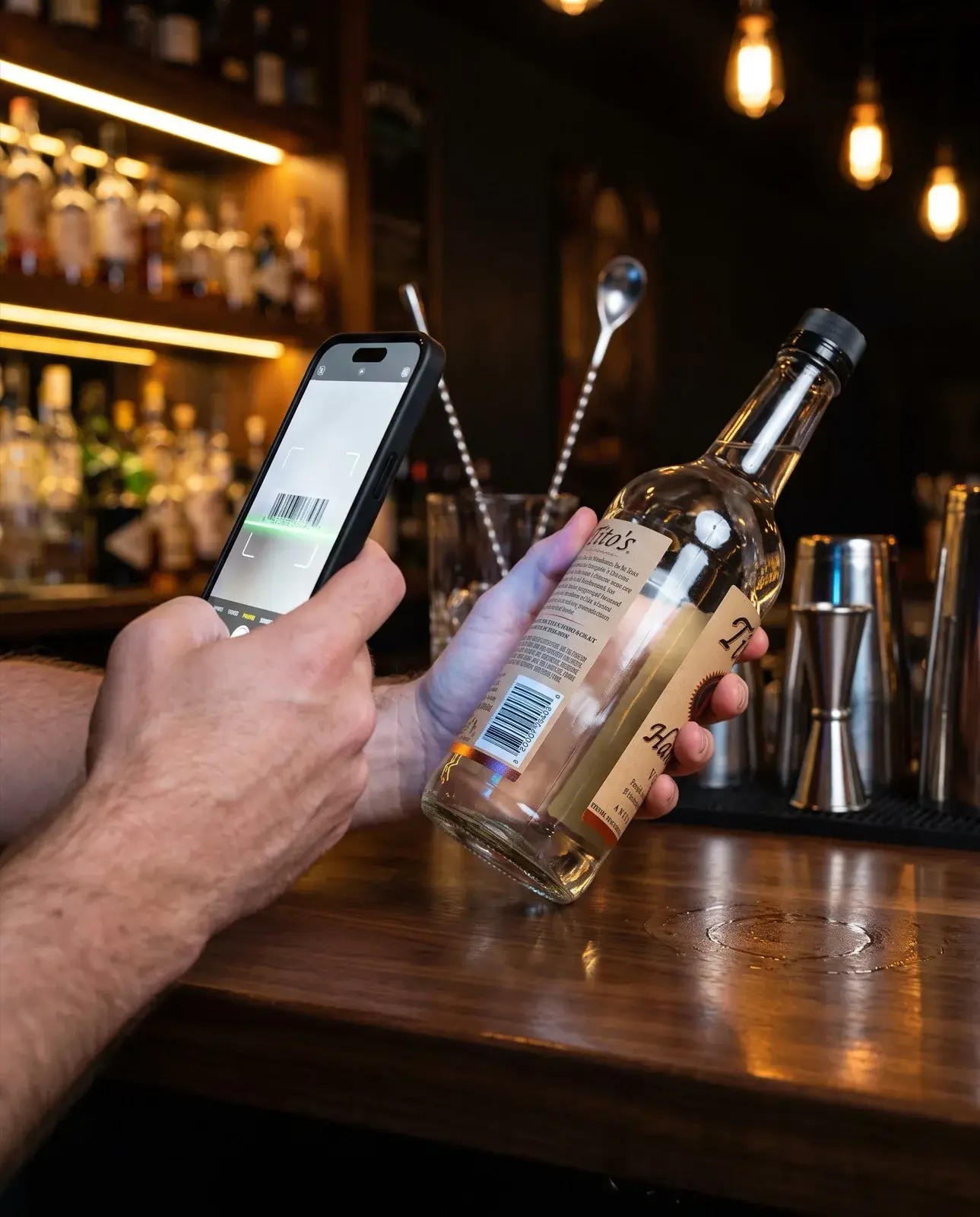 Scanning a liquor bottle barcode with a phone during a bar inventory count